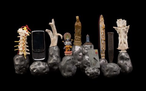 Fiona Hall Untitled (potatoes), 2014; lead, found objects including wooden Shiva, plastic Titanic, Blackberry mobile phone, wooden branch, model of spine, credit card, bone of a dugong, metal spike, plastic Madonna, car light; 11 parts: each approx. 15cm high; Enquire