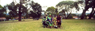 Anne Zahalka Bosun and Graace Adeyemi with children David, Elizabeth and Emmanuel, Mt Lewis, 2002, 2002; from the series West Nigerian family sitting on park bench in suburban park; Type C colour photograph; 50 x 150 cm; Edition of 12; enquire